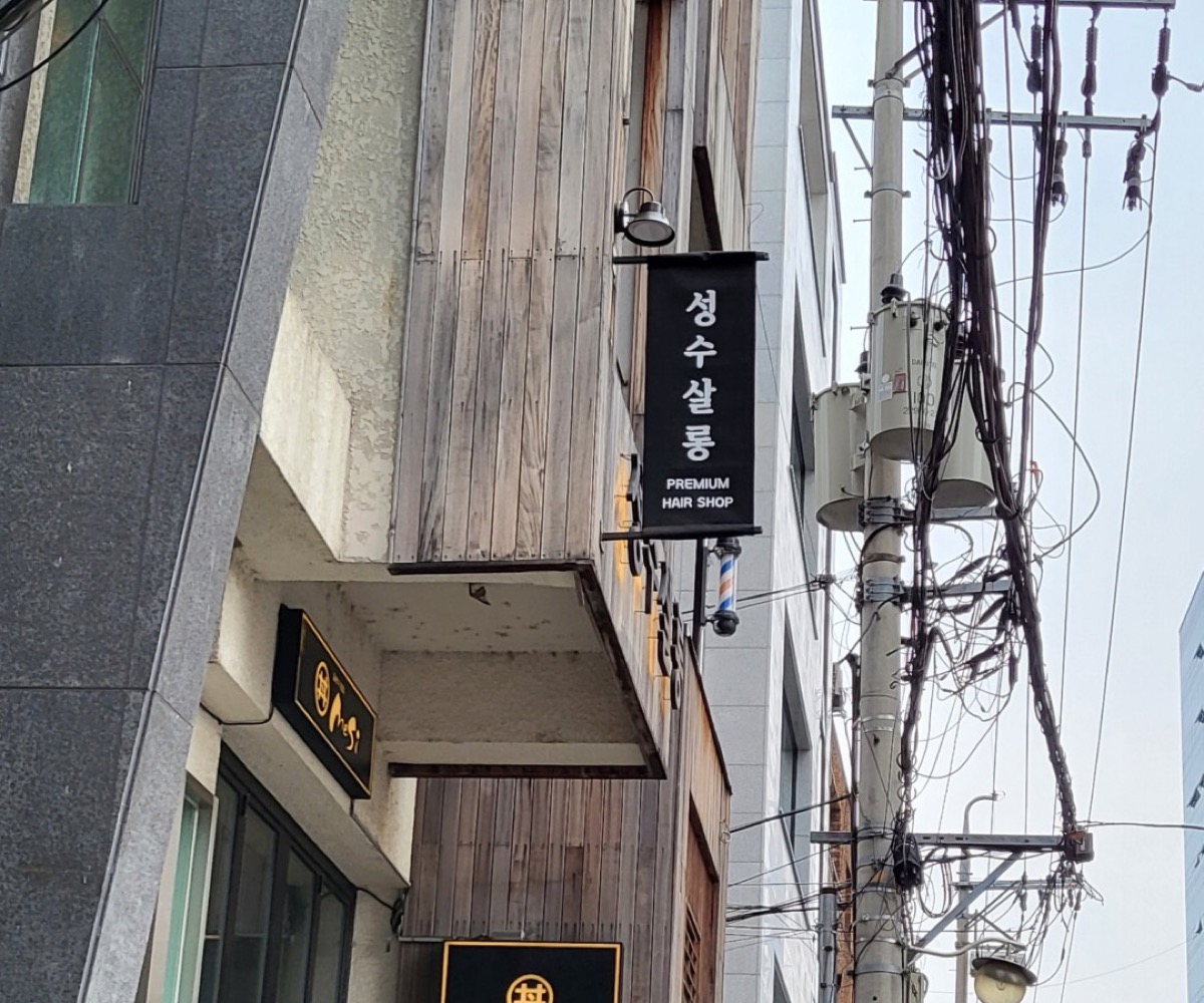 성수살롱 건물 외관. 2층 검은 세로 간판에 성수살롱 PREMIUM HAIR SHOP, 1층에 메시와 호미담 간판
